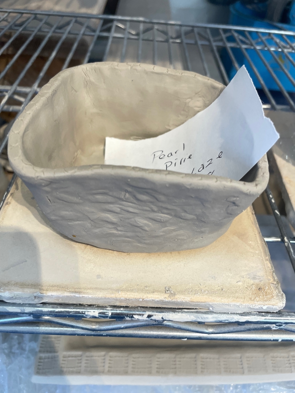 unfired squared clay bowl with slip of paper in it